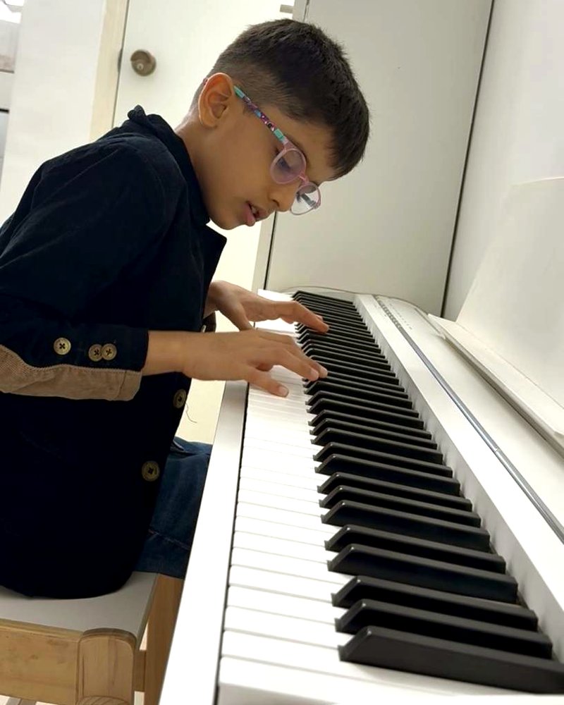 Aveer playing his piano at home, eyes on the keys